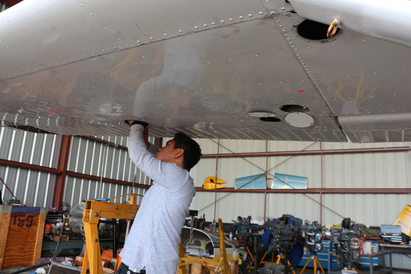 student under wing of airplane