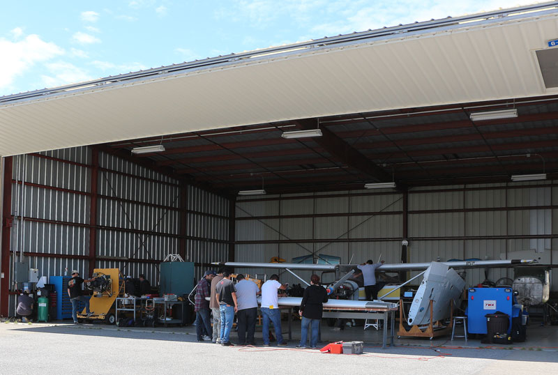 students with plane in hangar