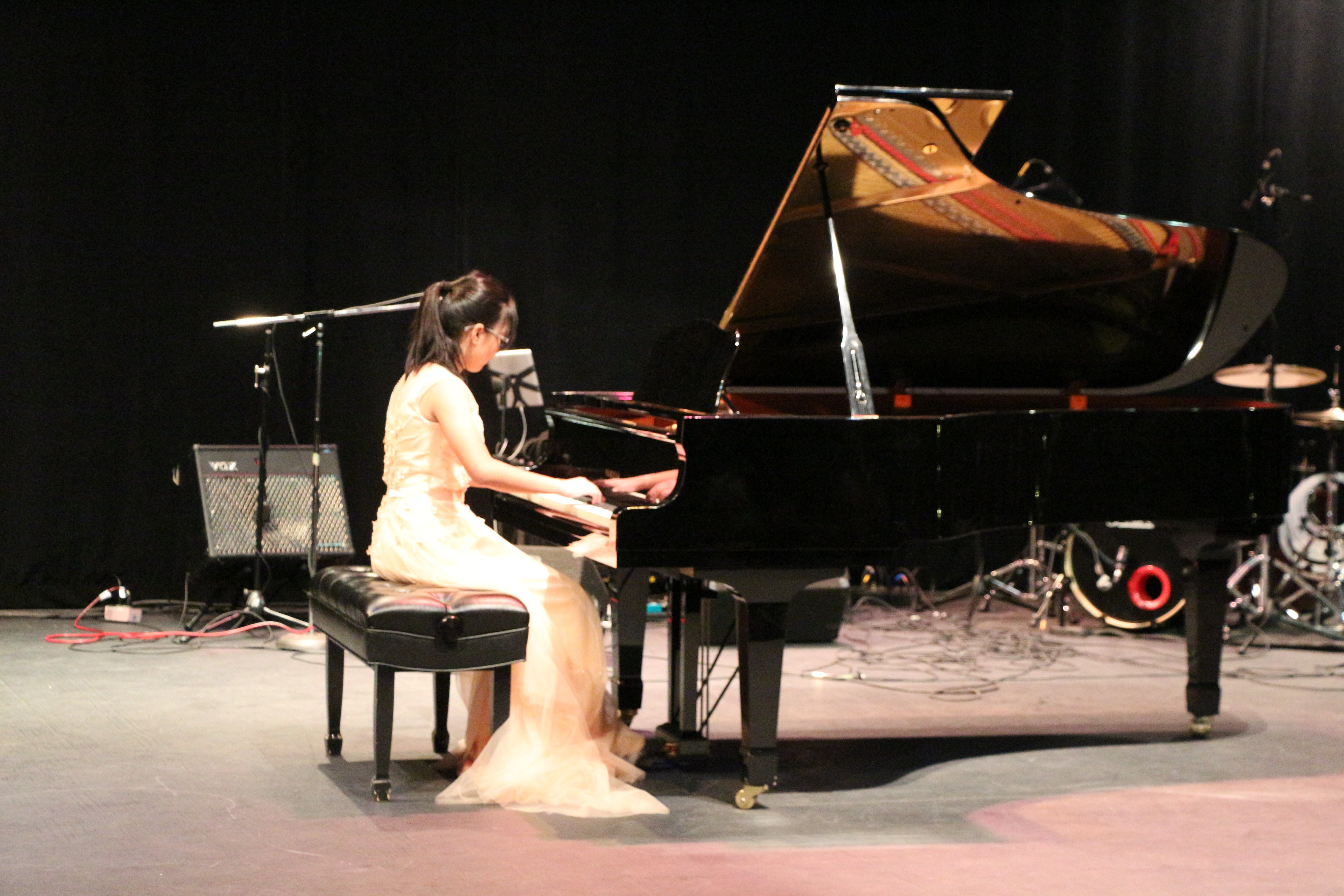 2019 Marian Filice Youth Piano Competition Local Prize Winner.  Female in white dress playing grand piano on stage. 