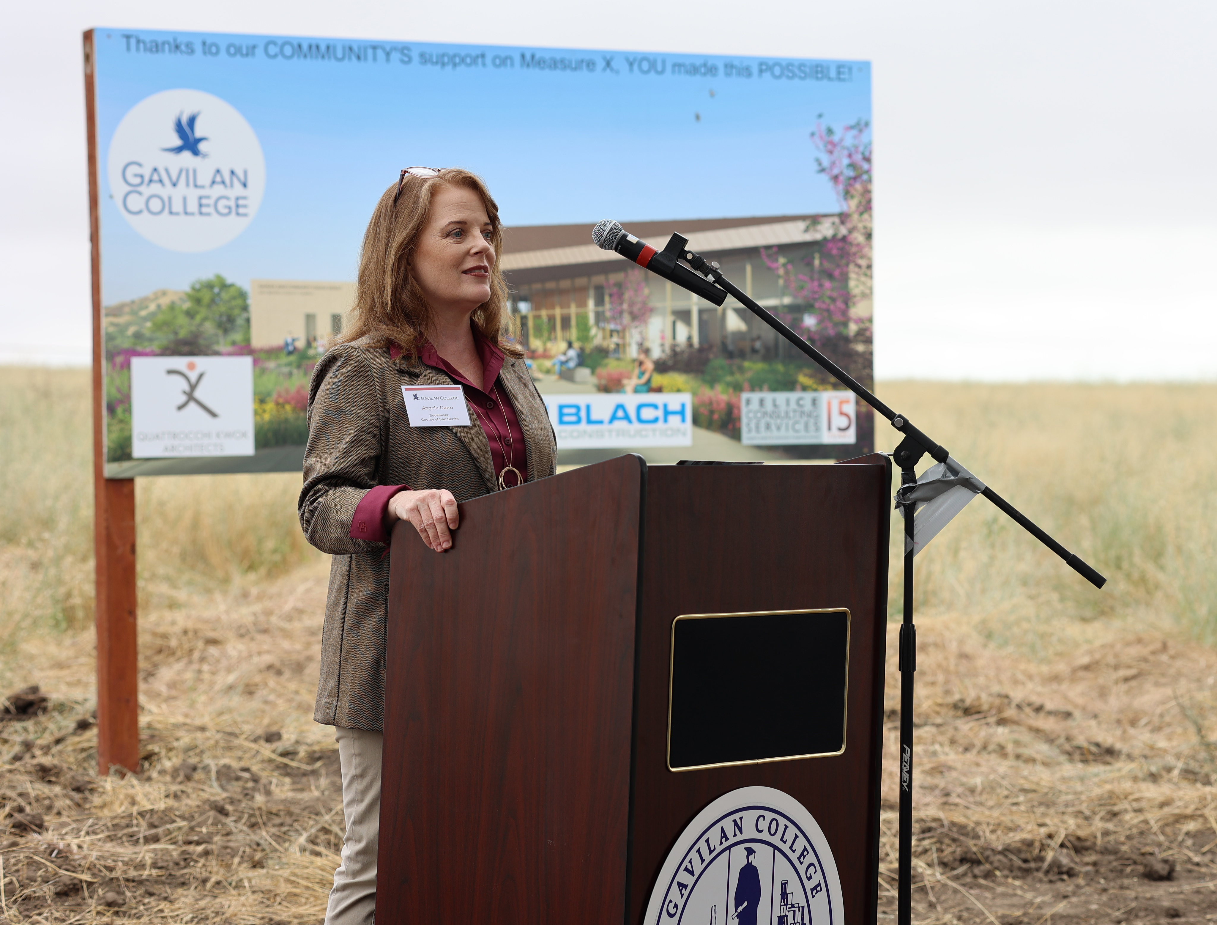 Angela Curro, Supervisor - County of San Benito, speaking at podium with Gavilan College seal.