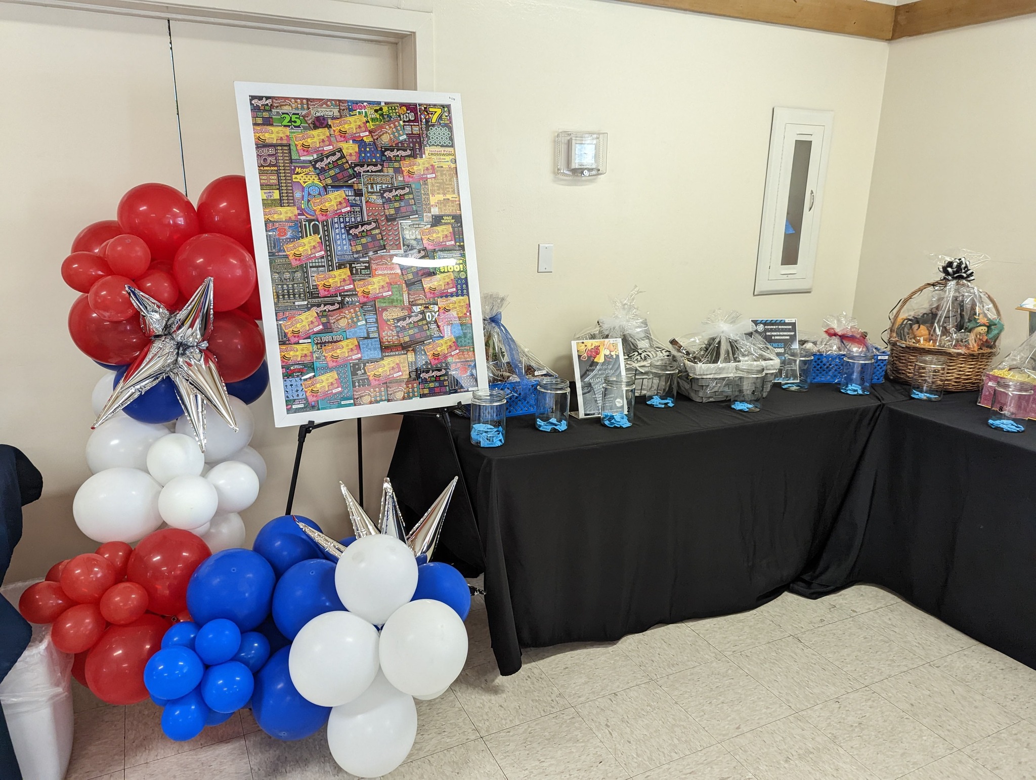 Framed lottery tickets and table with wrapped gift baskets.